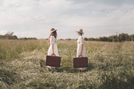 Téléchargez les photos : Deux femmes élégantes surréalistes habillées de la même façon avec une valise face à l'autre partent pour leur voyage, concept abstrait - en image libre de droit