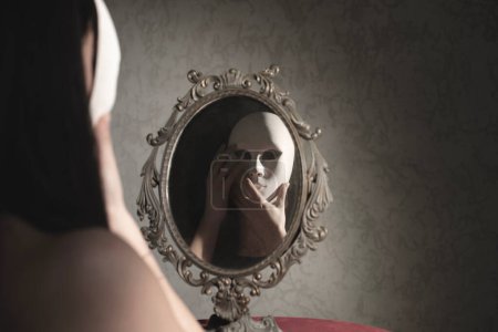 Photo for Woman in front of the mirror takes off her mask, abstract concept - Royalty Free Image