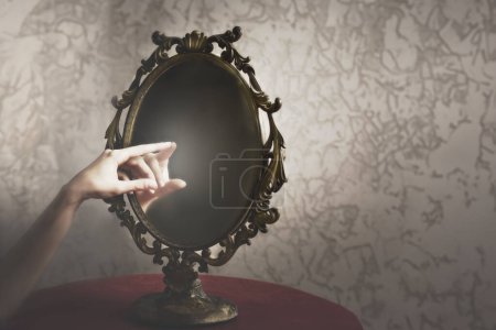 Téléchargez les photos : La main d'une personne touche sa main dans le reflet d'un miroir, concept abstrait - en image libre de droit