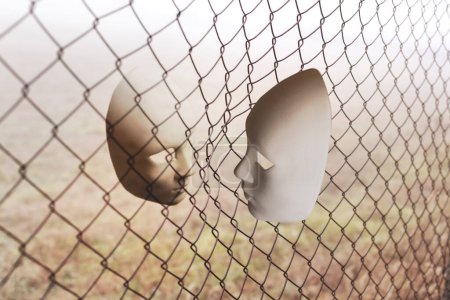 surreales Angesicht zu Angesicht zwischen zwei durch ein metallisches Netz getrennten Masken, abstraktes Konzept
