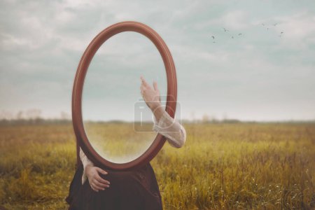 woman hides holding a mirror in front of her face and caresses it gently with her hand; concept of self love
