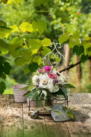 Téléchargez les photos : Bouquet de fleurs d'été avec des roses sur une table en bois dans un jardin - en image libre de droit