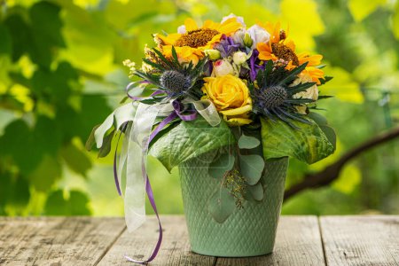 Téléchargez les photos : Bouquet de fleurs d'automne coloré dans une boîte en bois sur une table de jardin - en image libre de droit