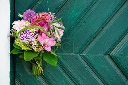 Foto de Ramo de flores de colores en una puerta de madera con espacio para copiar - Imagen libre de derechos