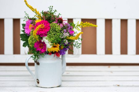 Photo for Colorful flower bouquet in a enamel pot on a garden bench - Royalty Free Image