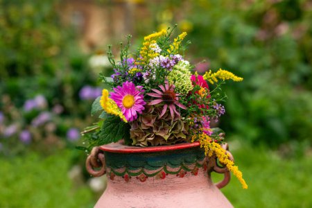 Téléchargez les photos : Bouquet de fleurs colorées sur une cruche à lait peinte dans un jardin - en image libre de droit