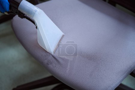 Close-up photo of upholstery vacuum-cleaner nozzle being used on top of a chair