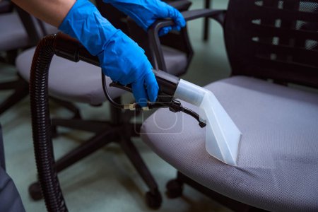 Photo for Skilled cleaning company worker deep-cleansing upholstery of chairs with a vacuum- cleaner - Royalty Free Image
