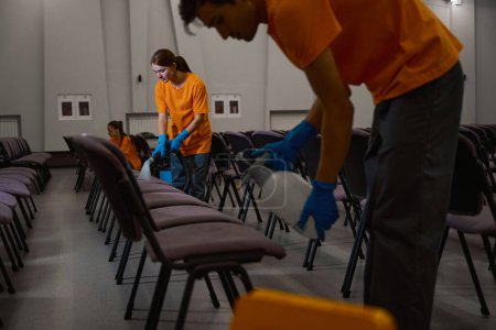 Photo for Professional team of cleaners working together on sanitizing the sitting area of the hall - Royalty Free Image