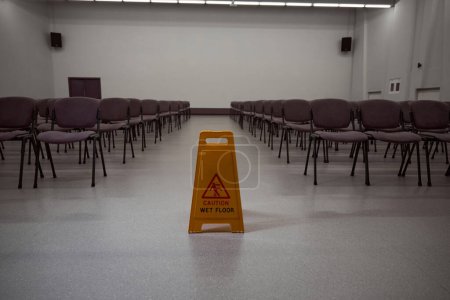 Foto de Ninguna foto de la gente de la señal de precaución amarilla en el medio de una habitación llena de sillas - Imagen libre de derechos