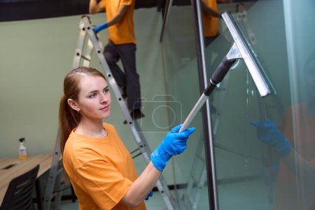 Téléchargez les photos : Employé de nettoyage professionnel utilisant des outils et des produits chimiques appropriés pour le nettoyage des fenêtres - en image libre de droit