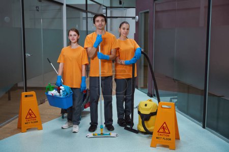 Photo for Friendly team of certified cleaners posing proudly with cleansing supplies and equipment while looking at the camera - Royalty Free Image