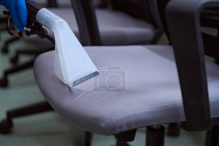 Photo for Cropped photo of a nozzle of upholstery vacuum-cleaner being used on a row of chairs - Royalty Free Image