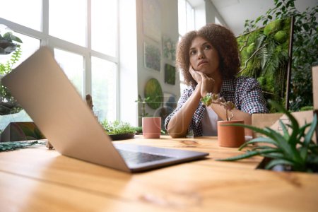 Photo pour Angle bas de jeune femme assise au bureau avec cahier et tasse de café tout en faisant des compositions vertes - image libre de droit