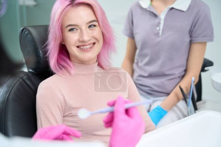 Foto de Mujer joven sonríe afablemente al médico, ella demuestra su sistema de soporte - Imagen libre de derechos