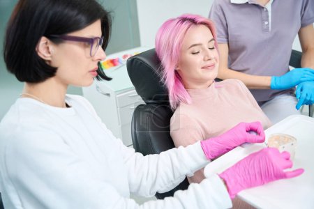 Foto de Mujer joven en una consulta con un ortodoncista, el médico utiliza material visual - Imagen libre de derechos