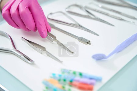 Téléchargez les photos : Ensemble d'instruments orthodontistes spéciaux se trouve sur la table chirurgicale, le médecin choisit une pince spéciale - en image libre de droit