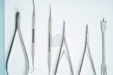 Téléchargez les photos : Instruments métalliques dentaires brillants reposent sur une surface légère, cet ensemble est utilisé en orthodontie - en image libre de droit