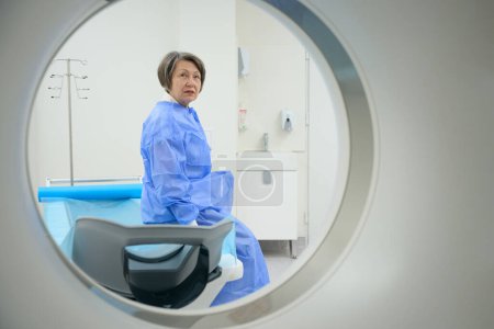 Foto de Woman looks into the camera of a modern CT machine, she is preparing for a diagnostic procedure - Imagen libre de derechos