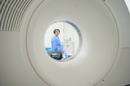 Foto de Elderly patient looks into the camera of a CT machine, she is preparing for a diagnostic procedure - Imagen libre de derechos