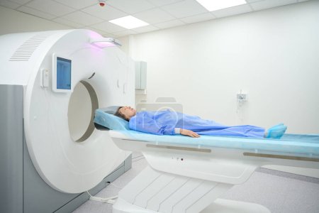 Foto de Woman lies on a special mobile surface of the MRI machine, she is in the diagnostic department of the hospital - Imagen libre de derechos