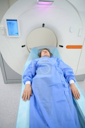 Foto de Patient, stretching her arms along the body, lies on the mobile surface of the CT machine, she is calm - Imagen libre de derechos