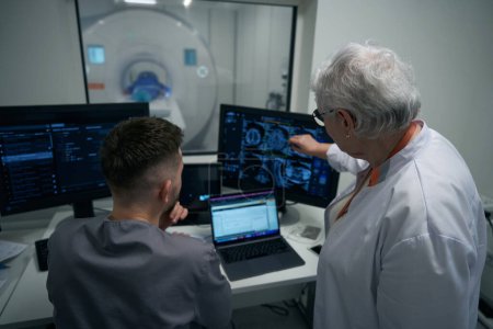 Photo for Doctors, a man and a woman, are looking through MRI images on a computer monitor, they are examining a patient - Royalty Free Image