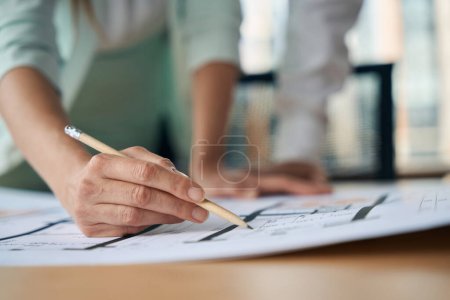 Photo for Selective focus photo of woman in stylish suit holding sharp pencil while editing details on the paperwork - Royalty Free Image