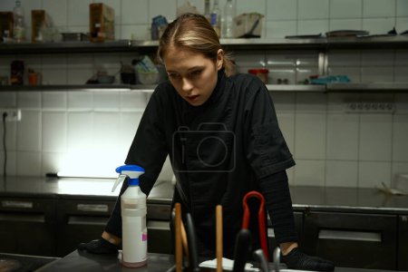 Téléchargez les photos : Upset woman is standing in the restaurant kitchen, she is resting from routine cleaning - en image libre de droit