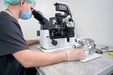 Photo for Embryologist behind the procedure of fertilization of the egg, the man uses modern equipment - Royalty Free Image