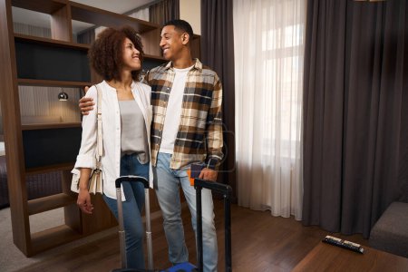 Téléchargez les photos : Photo de jeunes conjoints multiraciaux dans une chambre d'hôtel, dans une salle de design minimaliste - en image libre de droit