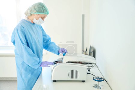 Téléchargez les photos : Hématologue met des échantillons dans une centrifugeuse dans une unité de test, c'est un laboratoire de diagnostic moderne - en image libre de droit
