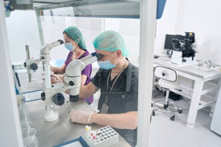 Téléchargez les photos : Homme et femme travaillent dans un laboratoire moderne, autour d'équipements spéciaux et de tubes à essai - en image libre de droit