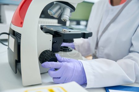 Foto de Genetista en la unidad de pruebas estudia biomaterial para una prueba de ADN, un especialista utiliza un microscopio - Imagen libre de derechos