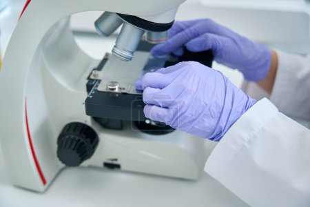 Foto de Geneticist laboratory assistant in the testing unit studies biomaterial for a dna test, a specialist uses a powerful microscope - Imagen libre de derechos