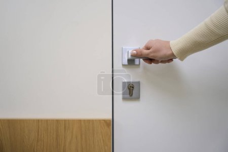 Foto de El hombre sostiene su mano en el pomo de la puerta, hay una cerradura en la puerta - Imagen libre de derechos