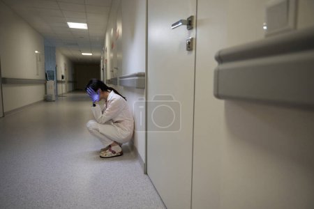 Photo for Full length side view portrait of qualified doctor is sitting with head down in the hospital - Royalty Free Image