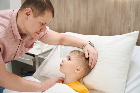 Téléchargez les photos : Vue de côté portrait de magnifique petit garçon nerveux parle avec son père dans le service médical - en image libre de droit