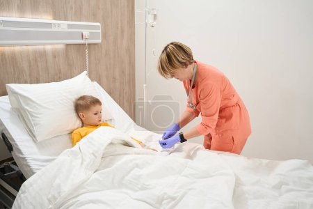 Foto de Retrato de vista lateral de longitud completa de la hermosa enfermera está preparando la medicina para el niño en la sala médica - Imagen libre de derechos