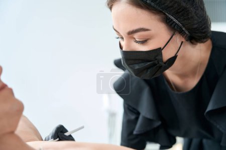 Foto de Mujer con guantes protectores sosteniendo la jeringa y haciendo inyecciones de belleza en axila al hombre - Imagen libre de derechos