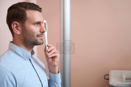 Téléchargez les photos : Taille vers le haut vue de côté portrait de beau homme caucasien vérifie sa vue dans la clinique opticien - en image libre de droit