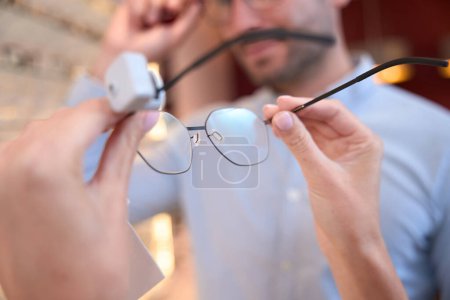Photo for Close up image of female hands is holding the optician frame and choosing it for the gift in the luxury store - Royalty Free Image