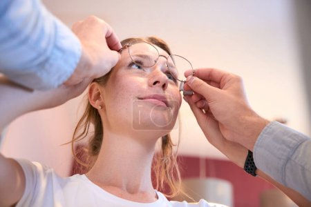 Foto de Retrato de ángulo bajo de hermosa mujer caucásica está eligiendo las gafas de ojo moderno en la tienda de óptica moderna - Imagen libre de derechos