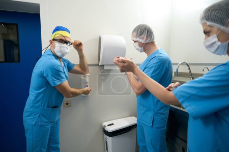 Téléchargez les photos : Préparation préliminaire du personnel médical pour une opération chirurgicale, les gens utilisent un désinfectant spécial - en image libre de droit