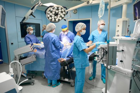 Foto de Equipo de médicos trabaja en un quirófano moderno, hay un montón de equipo especial en la habitación - Imagen libre de derechos