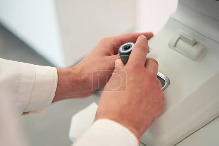 Photo for Close up portrait of man hands is operating slit lamp in the modern medical clinic - Royalty Free Image