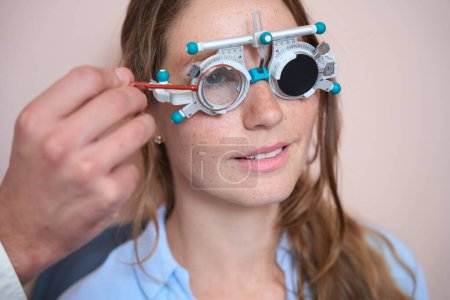 Photo for Close up portrait of happy cheerful Caucasian female is getting qualified eyesight test in optician cabinet - Royalty Free Image