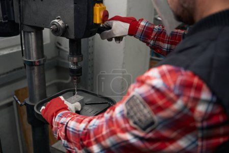 Photo for Man in protective mask and gloves using drilling machine to making hole in detail - Royalty Free Image