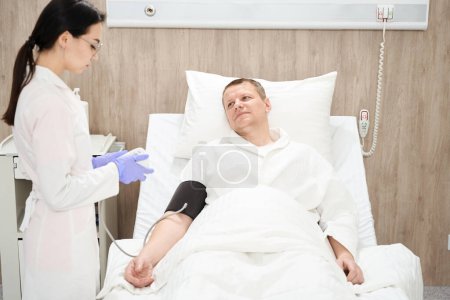 Foto de Vista frontal retrato de hombre caucásico adorable está recibiendo tratamiento y el examen de su salud en el hospital moderno - Imagen libre de derechos