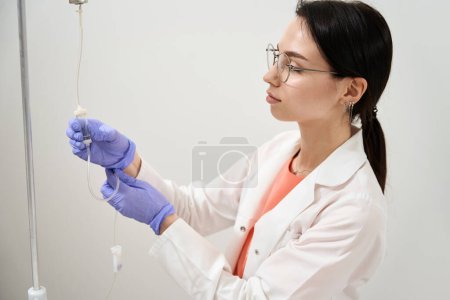 Photo for Close up side view portrait of beautiful elegant female nurse is preparing medicine dropper in the hospital - Royalty Free Image